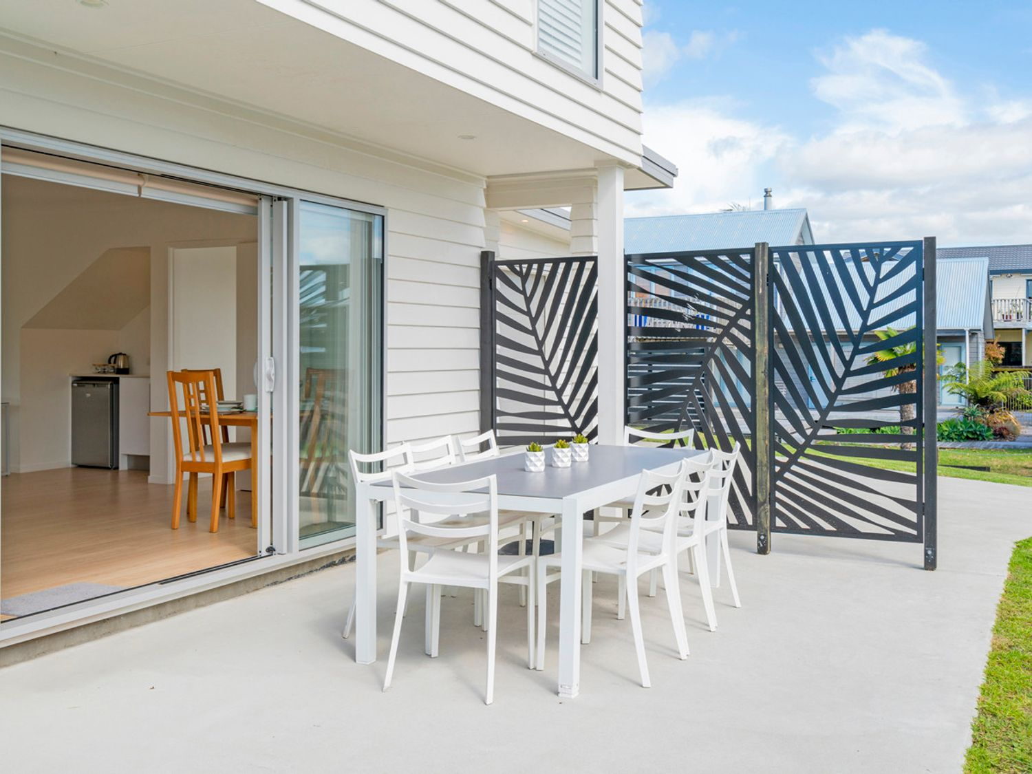 Outdoor dining area on the deck at Coastal Pearl Matarangi at dusk